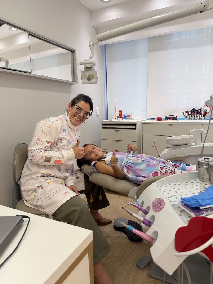 Dra. Danielle Rocha ao lado de uma pequena paciente, no consultório